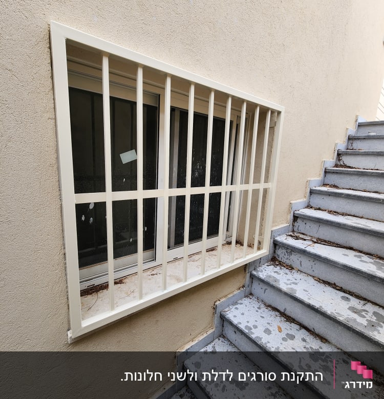 חלון עם סורגים לבנים ליד מדרגות בטון